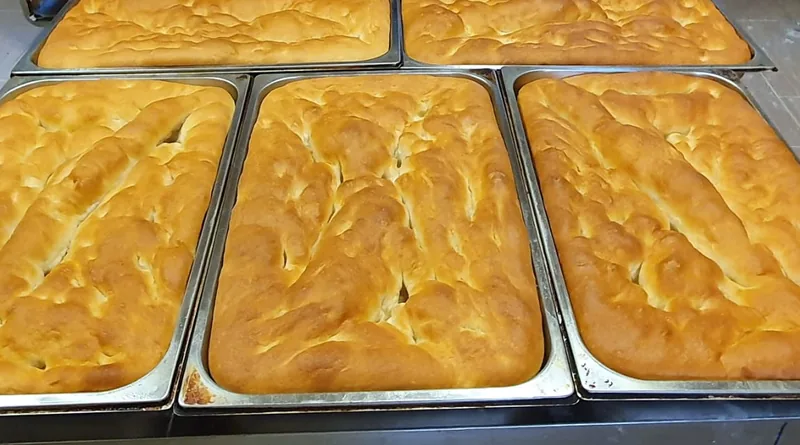 Focacce bianche appena sfornate nelle teglie d'acciaio