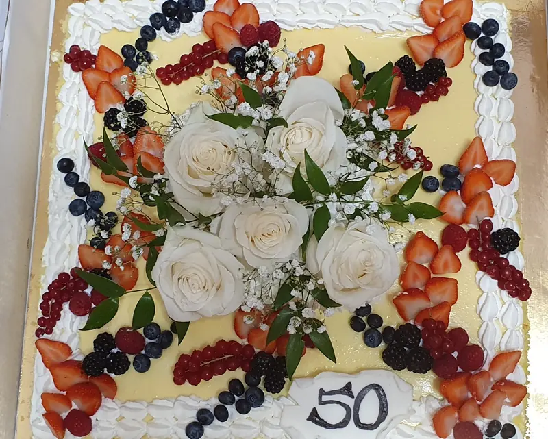 Torta con rose bianche, frutti di bosco e placca 50